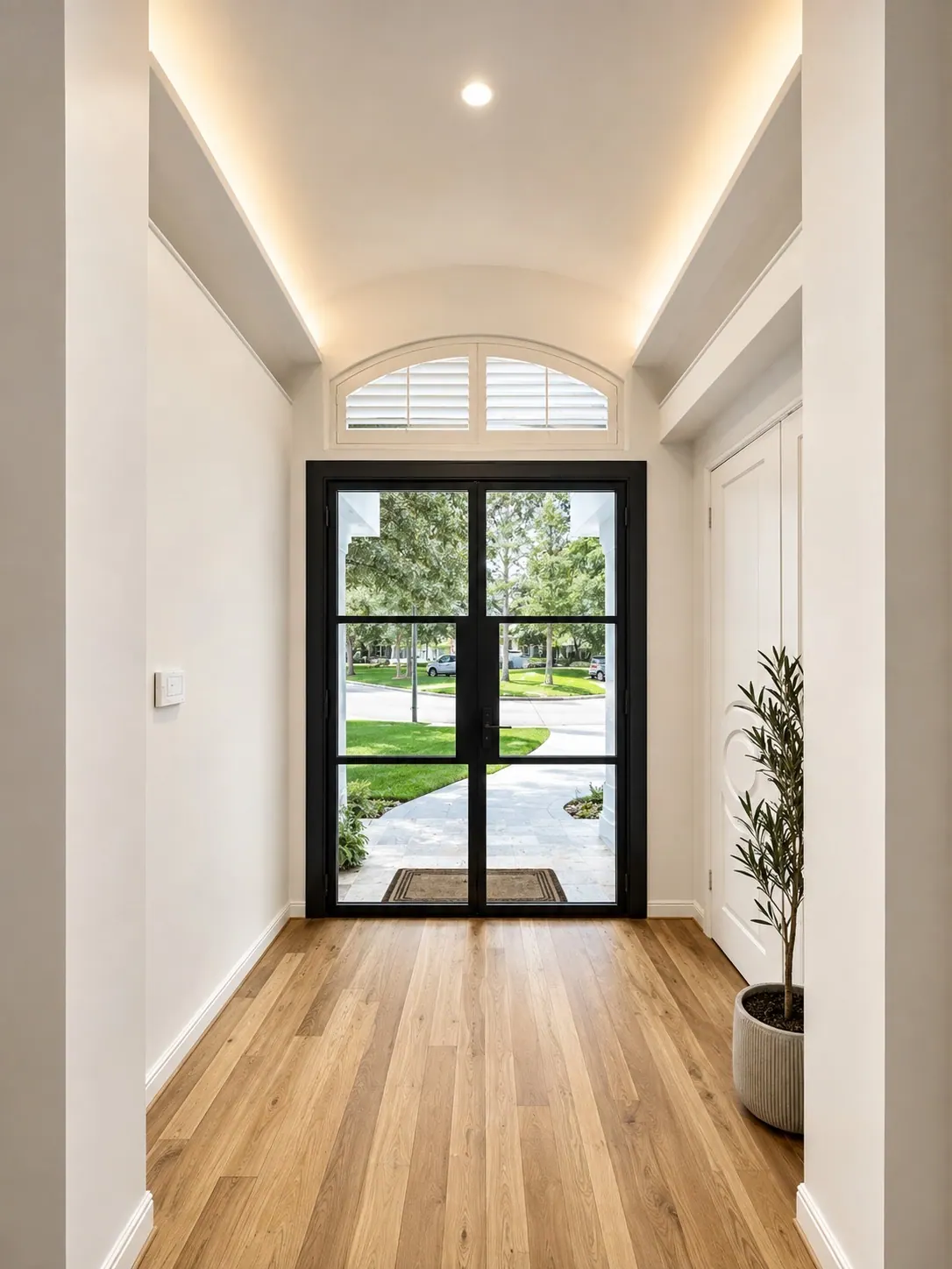 Black iron double doors at the end of a bright hallway