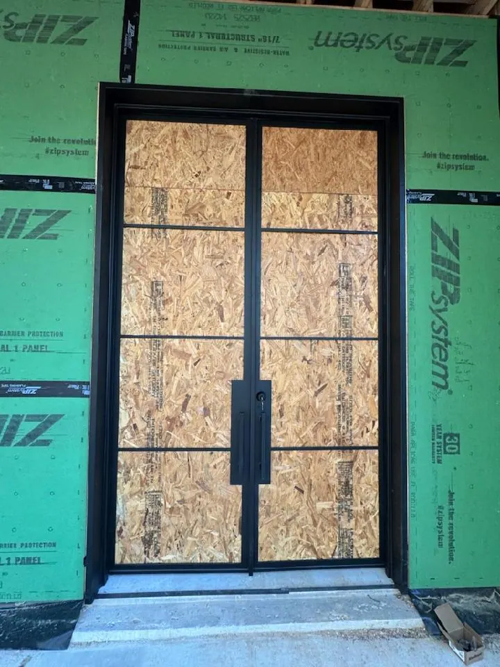Black iron double doors protected during construction