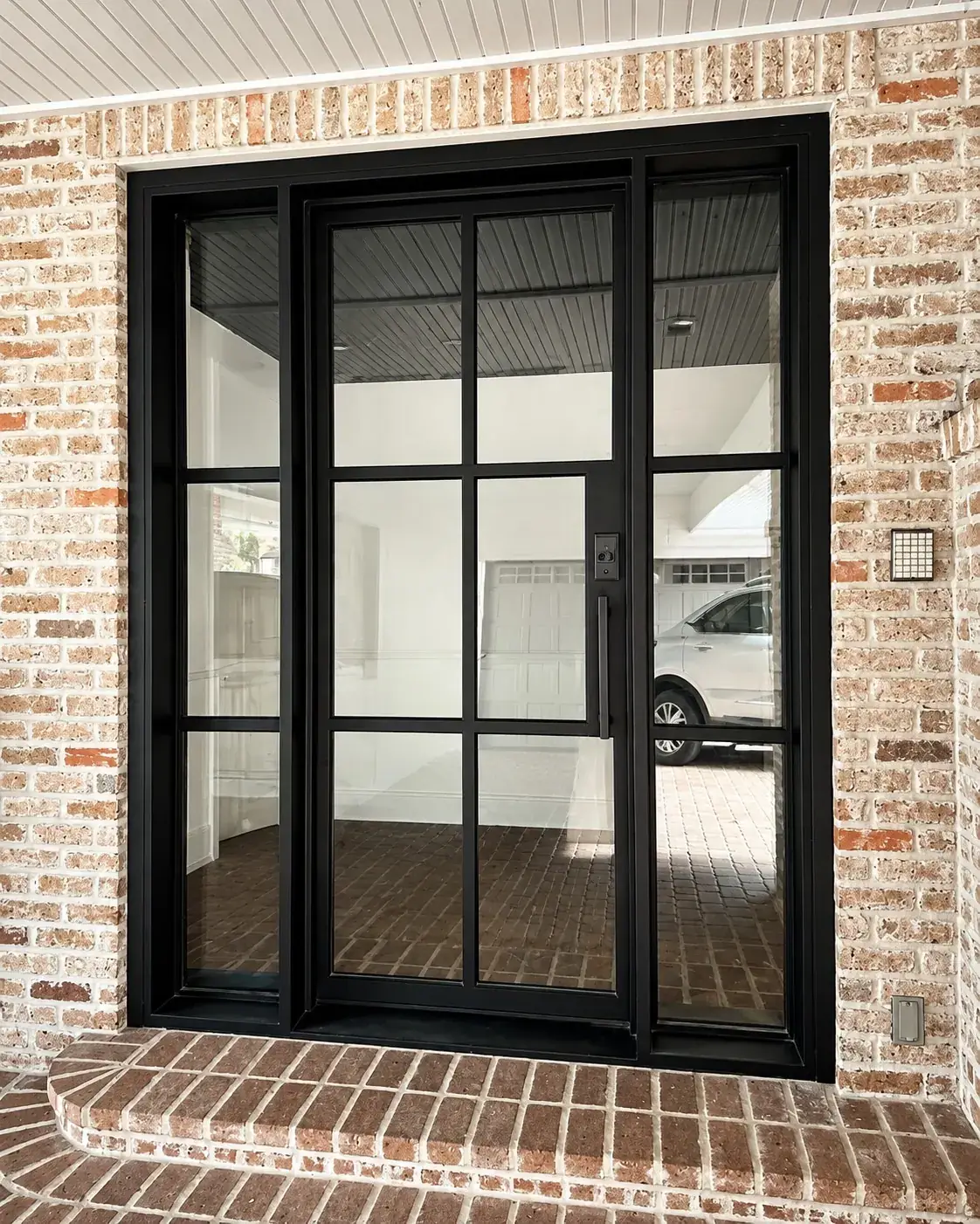 Black iron double door with sidelights on a brick home