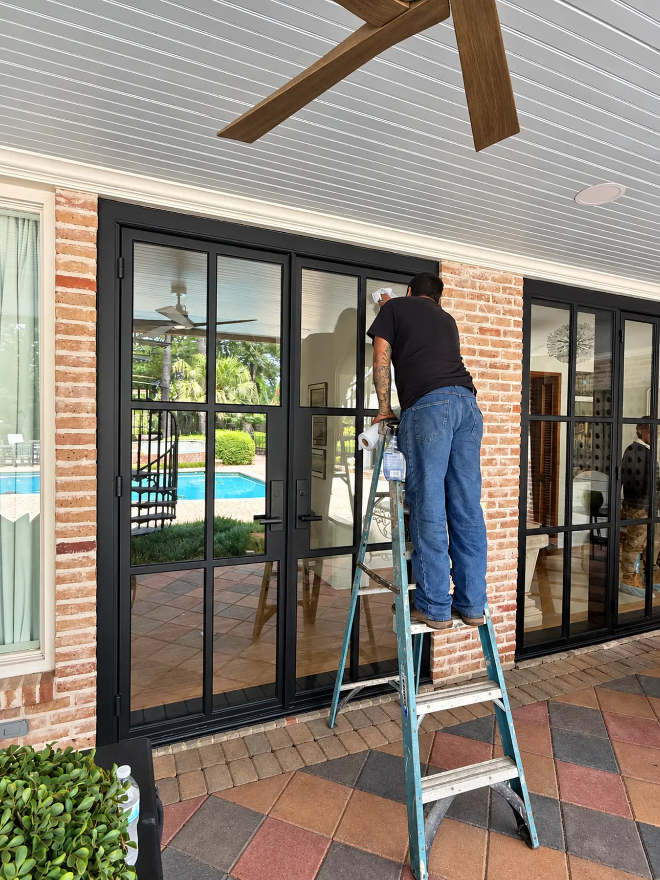 Blackline installer cleaning the glass of new iron French doors