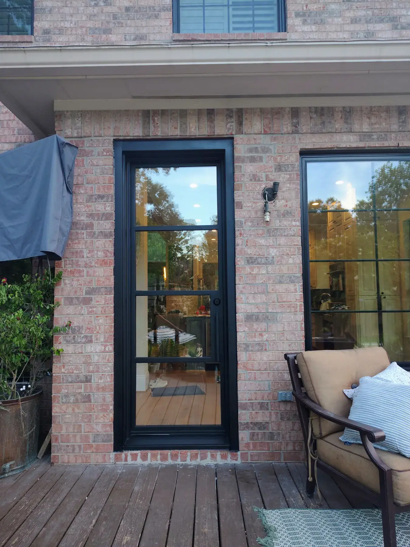 Single black iron patio door on a brick wall with a deck