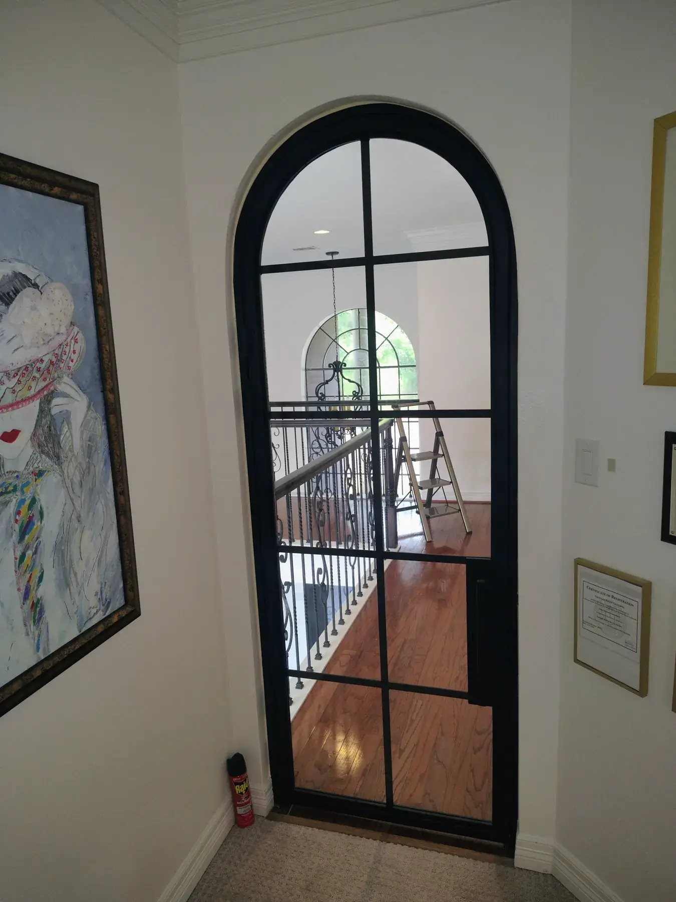 Arched black iron door next to a stair railing