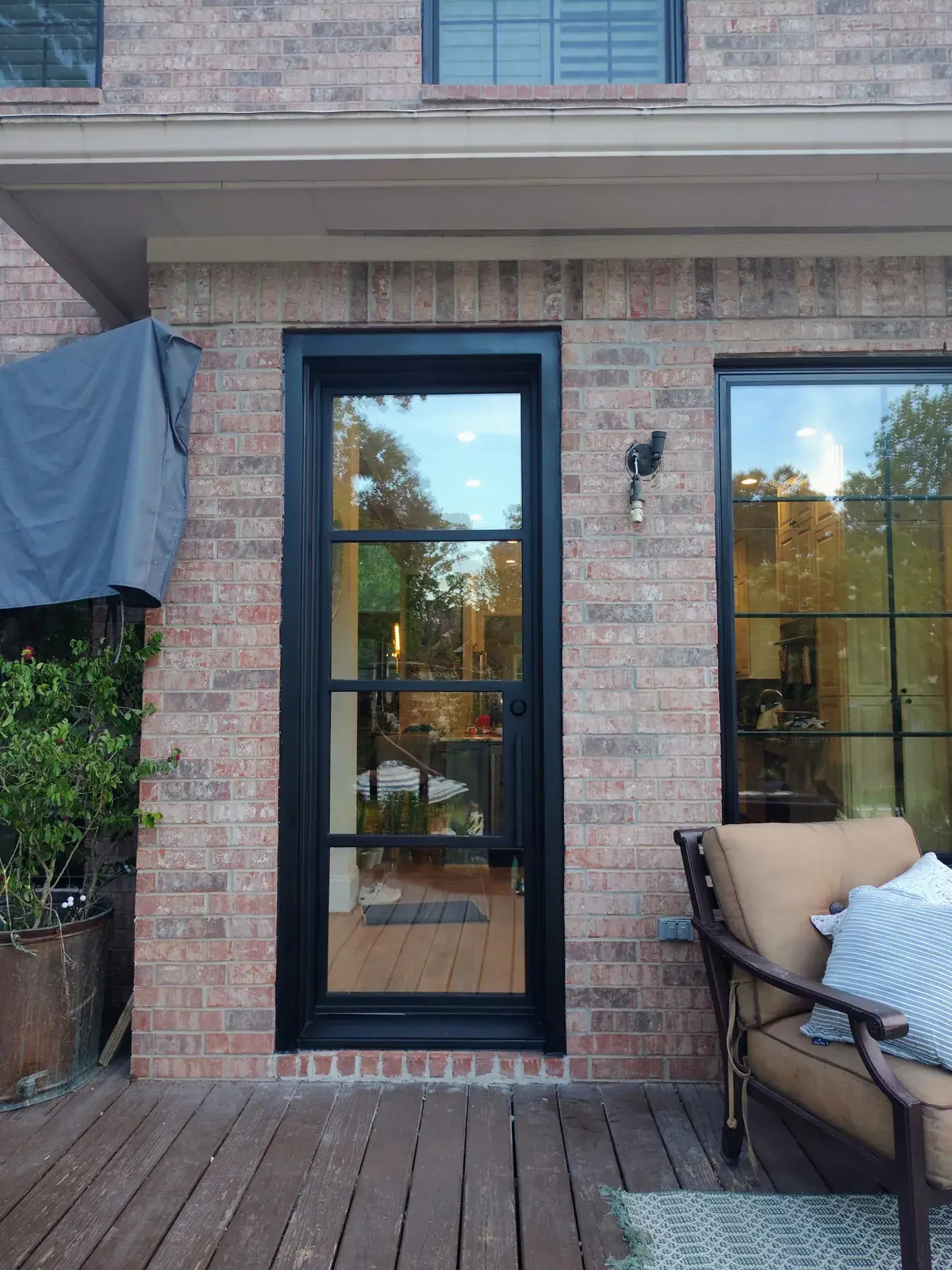 Tall single black iron door on a brick patio